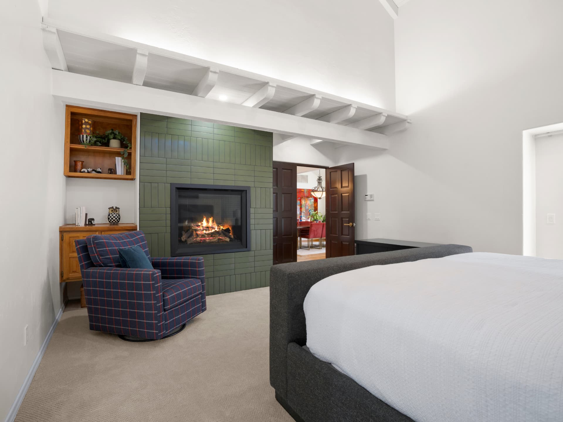 Primary bedroom with beamed vaulted ceiling and tiled gas fireplace