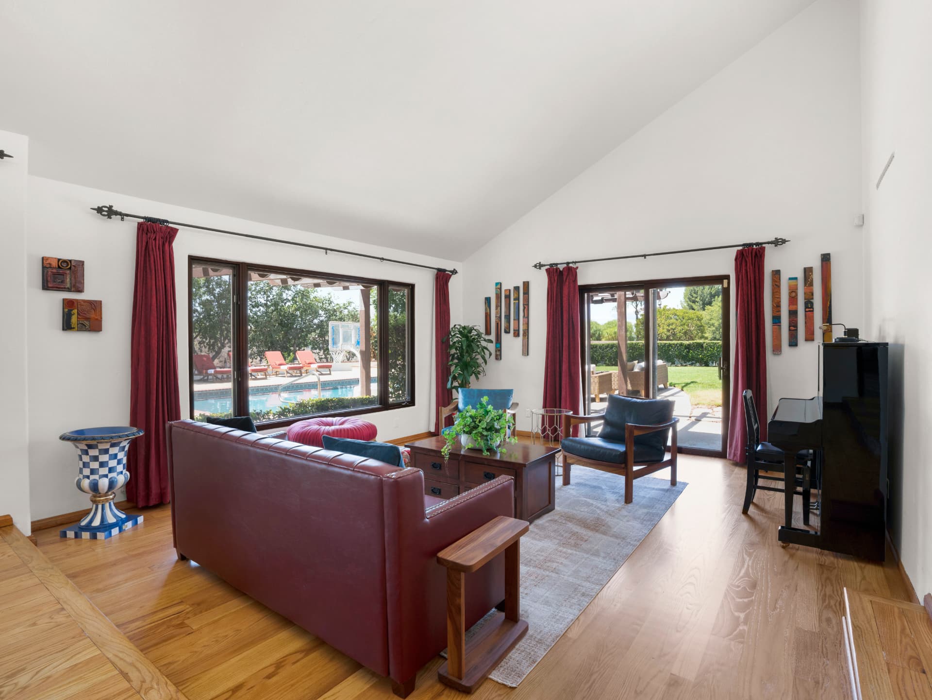 Formal living room with vaulted ceiling and windows overlooking the pool