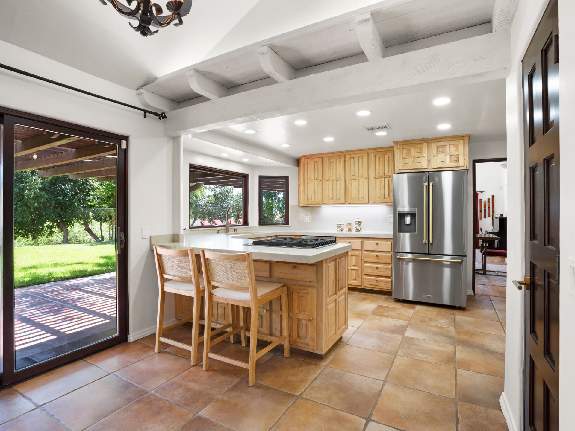 Kitchen with custom wood cabinetry, stone island and sliding doors to the patio